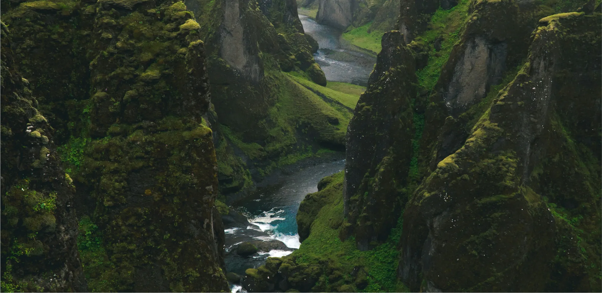 Top down view of a richly green mountainous landscape with a winding river flowing through it.